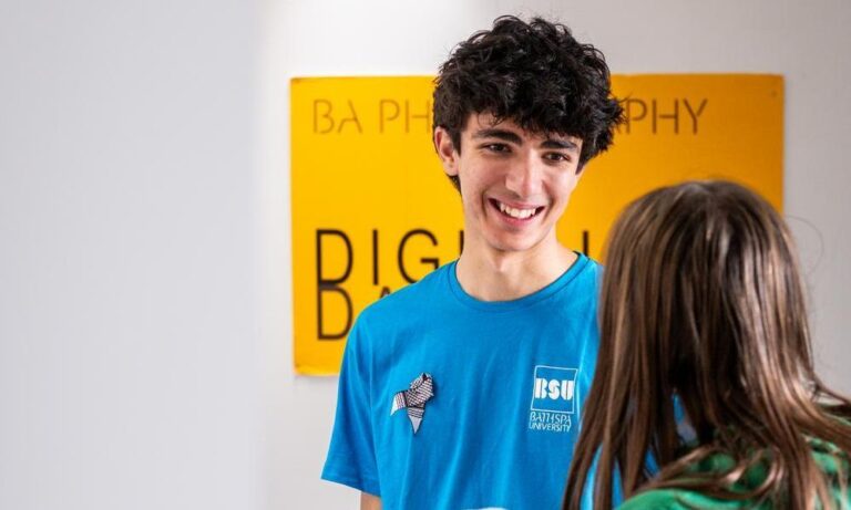 Bath Spa University open day welcome desk male student greeting potential student